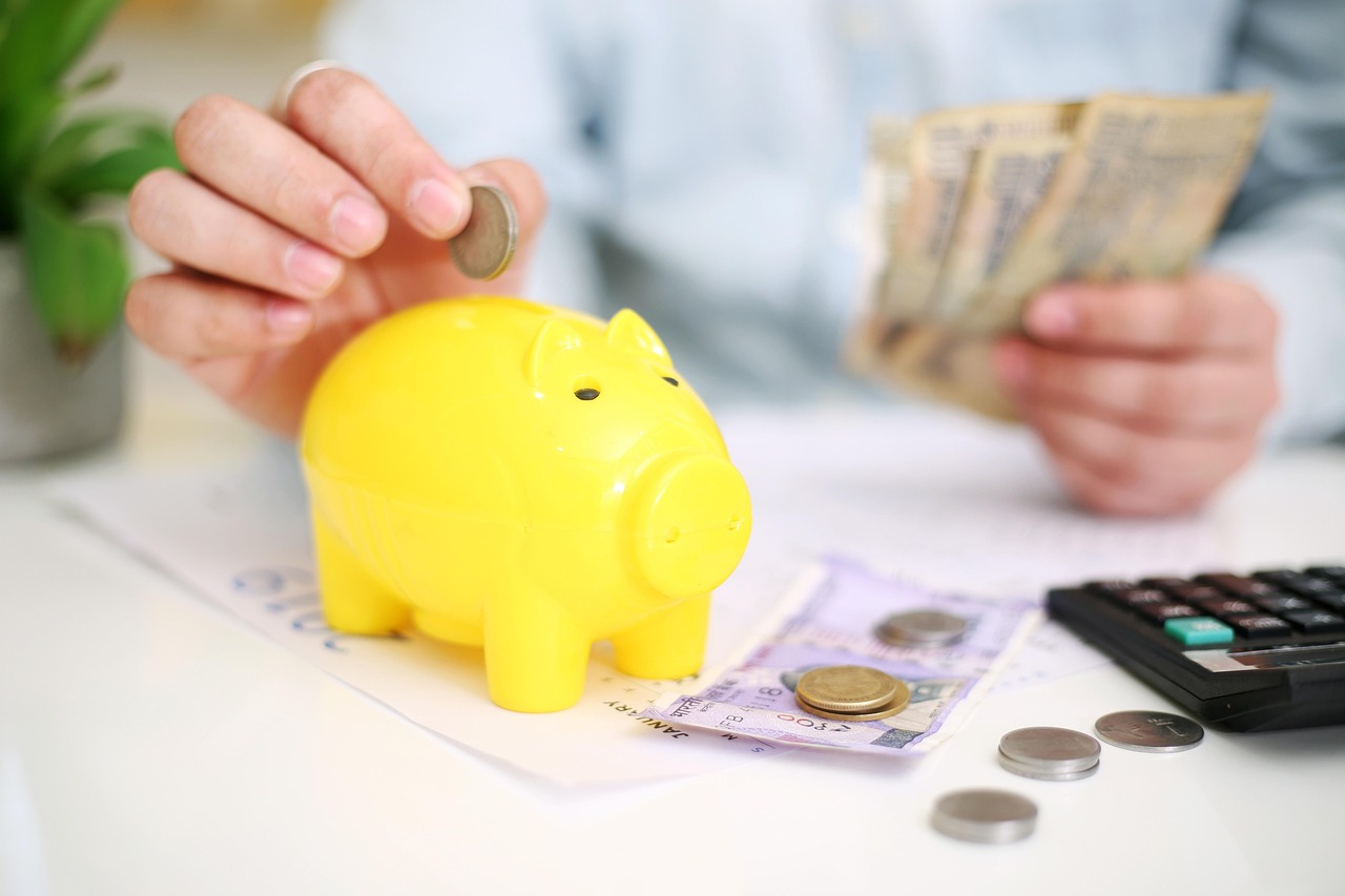Moedas, notas e calculadora destacando o efeito dos juros na velocidade de quitação das dívidas.