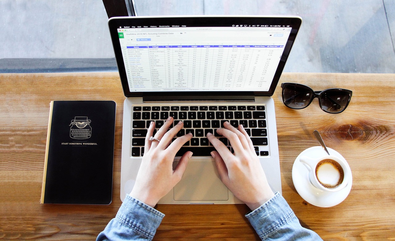 Notebook com planilha no computador e café, para registrar todas as dívidas antes de decidir o uso do 13º