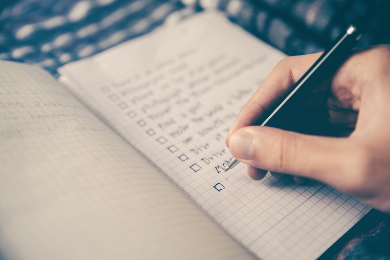Checklist em caderno com caneta e notebook, mostrando os campos essenciais da planilha de dívidas